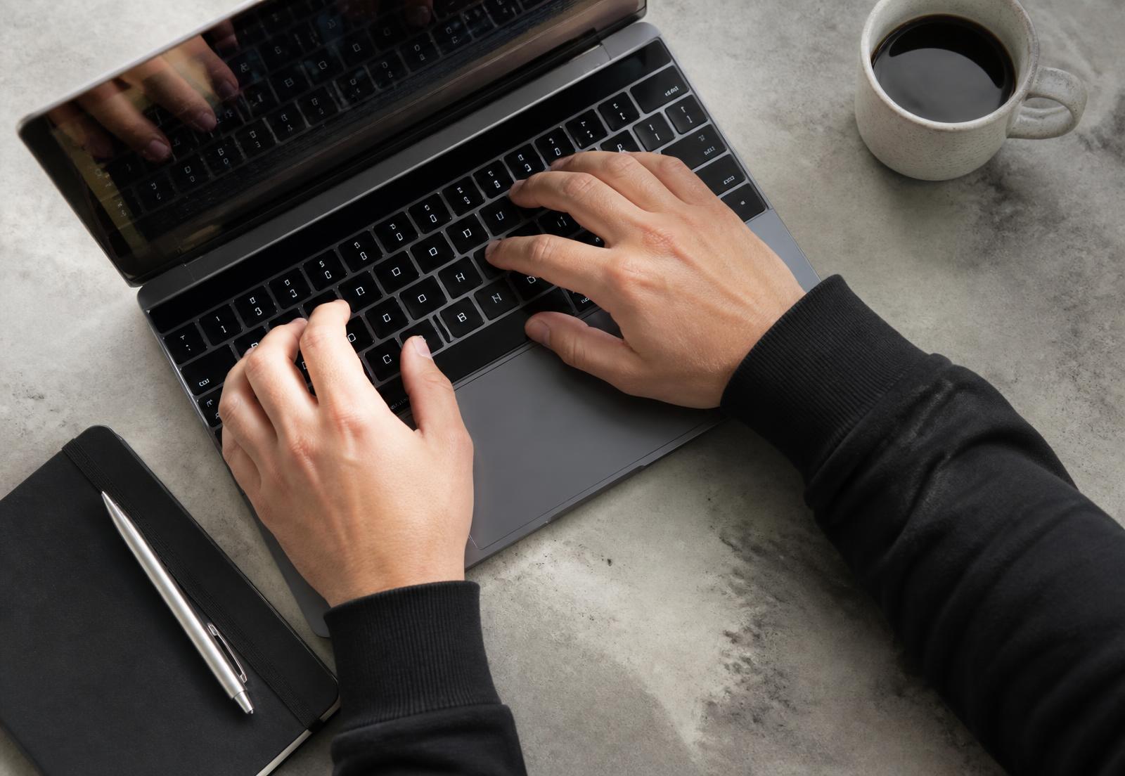 Handen typend op een laptop tijdens een werksessie